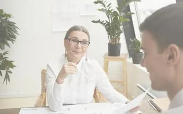 Dos profesionales revisando un documento junto al ordenador